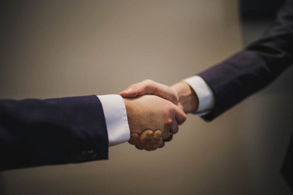 Kaksi henkilöä kättelemässä. Sovittelu on tuomioistuinprosessia halvempi ja nopeampi vaihtoehto.