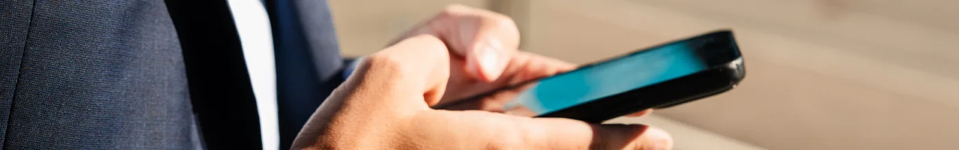Lähikuva lakimiehestä kirjoittamassa kännykällä viestiä asiakkaalle.