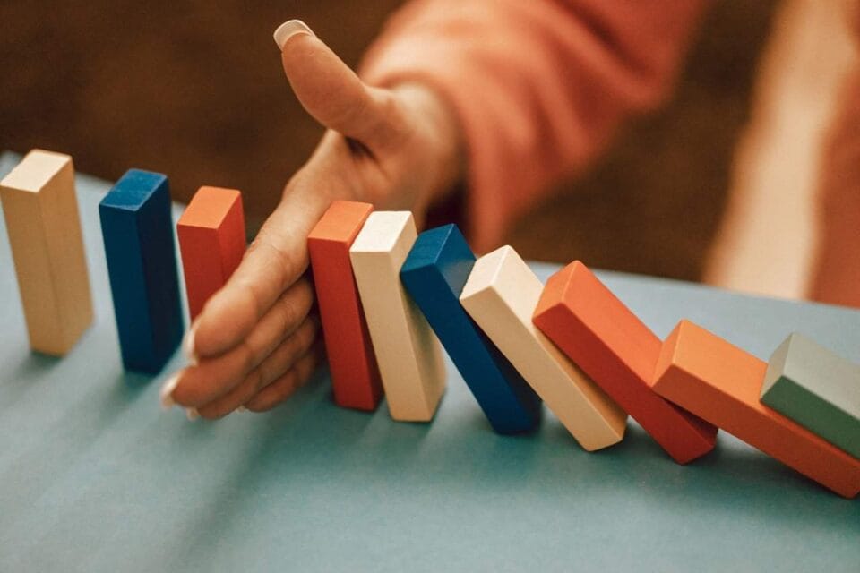 Domino-peli ja käsi välissä. Artikkelissa käsittelemme työnantajan varoituskäytäntöä. Milloin työnantaja voi antaa varoituksen?|
